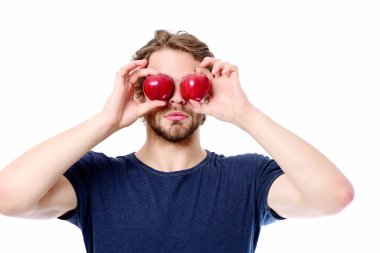 Mavi tişörtlü, genç sakallı bir adam, elinde göz olarak elma tutuyor.