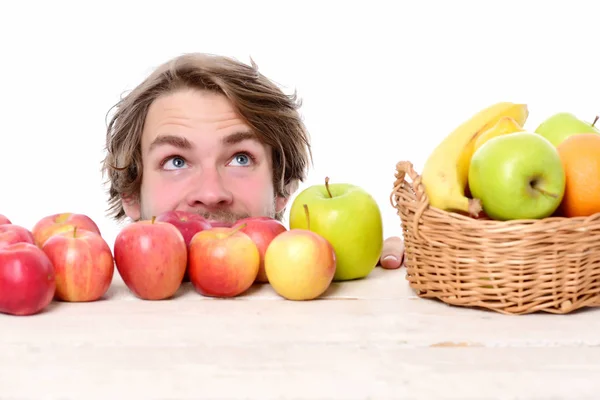 Joven hombre caucásico mirando hacia arriba con sonrisa feliz detrás de las manzanas — Foto de Stock