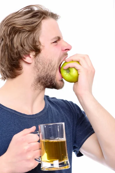 Facet kaukaski gryzienie zielone jabłko i przytrzymując szklanka do piwa — Zdjęcie stockowe