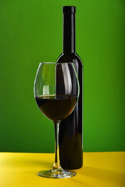 Sklenici s červeným vínem poblíž temné láhve — Stock fotografie