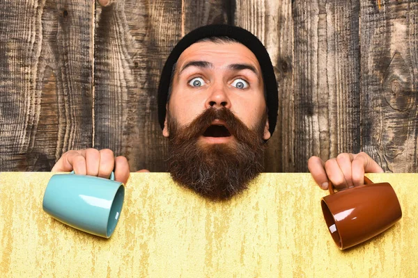 Barbudo brutal hipster caucásico con hoja de papel y tazas —  Fotos de Stock