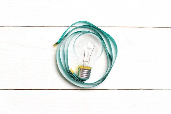 Light bulb in circle of cyan blue measuring tape — Stock Photo, Image