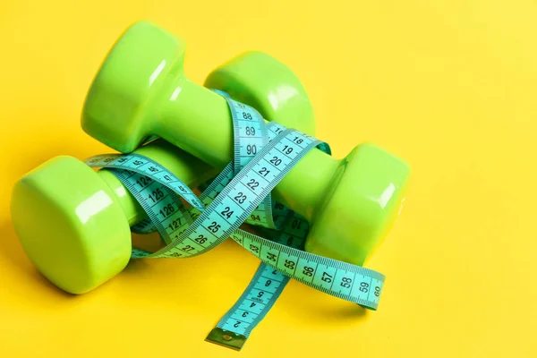 Weight loss concept with dumbbells and measuring tape — Stock Photo, Image