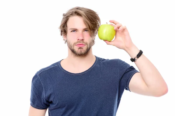 Чоловік у блакитній сорочці уважно дивиться і тримає зелене яблуко — стокове фото