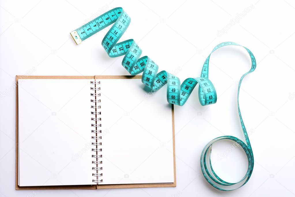 Notebook with open blank pages on binder and measuring tape