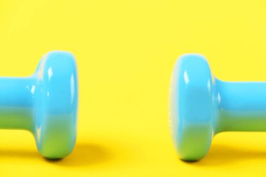Sarı arka plan üzerinde izole plastik kaplı dumbbells üst kısımları
