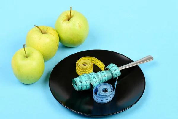 Manzanas cerca de la placa con reglas flexibles de colores y tenedor de metal —  Fotos de Stock