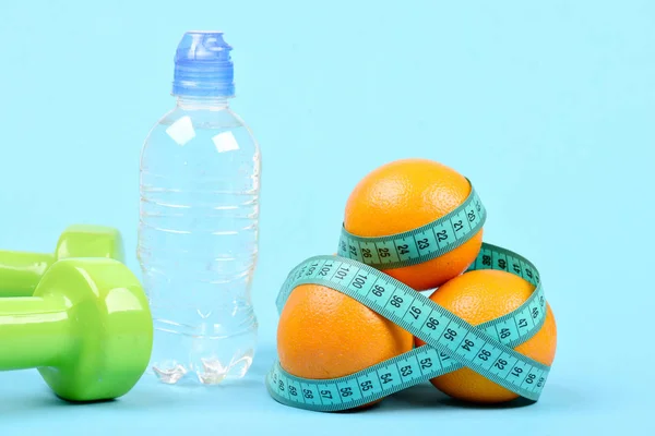 Agua en botella de plástico cerca de pesas y montón de naranjas — Foto de Stock