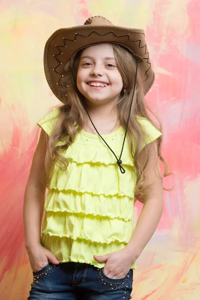 Barn, litet leende flicka i cowboy hatt på färgstarka bakgrund — Stockfoto