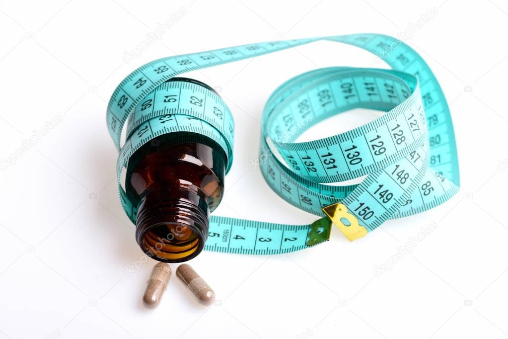 Concept of dietary nutrition: pills and bottle with measuring tape