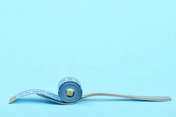 Fork made of metal and roll of blue measuring tape — Stock Photo, Image