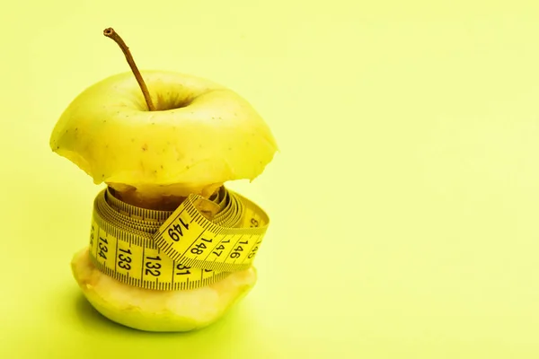 Äpple med måttband runt det på gul bakgrund — Stockfoto