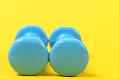 Parlak sarı zemin üzerine plastik hafif dumbbells çifti