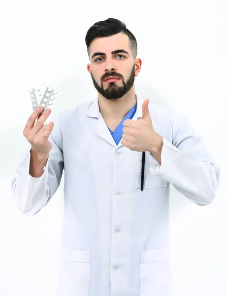 Doctor with stylish haircut and beard holds pills in hand — Stock Photo, Image