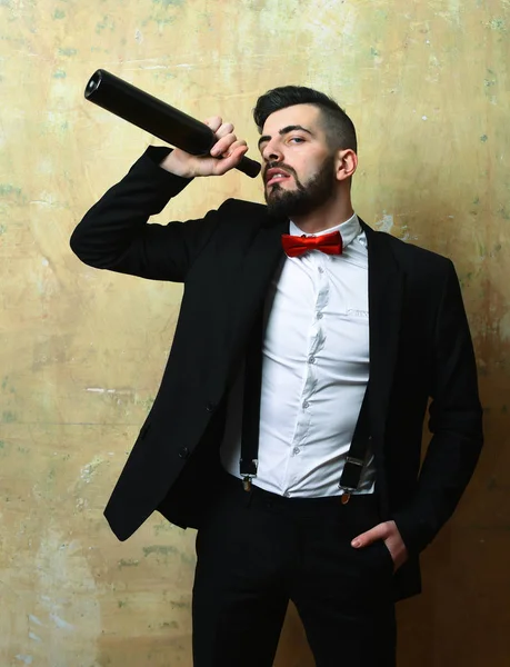 Człowiek z brodą w garniturze i czerwonym łukiem pije wino — Zdjęcie stockowe