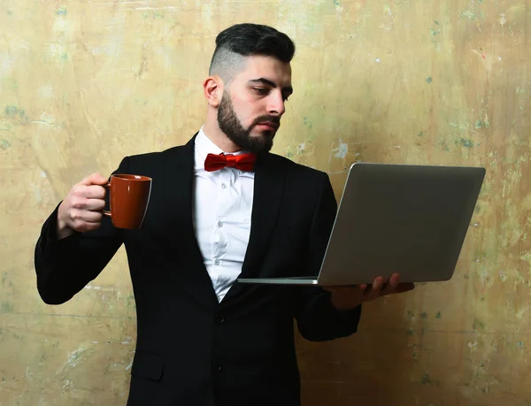 Bedrijf werknemer met drukke denken gezicht houdt cup en laptop — Stockfoto