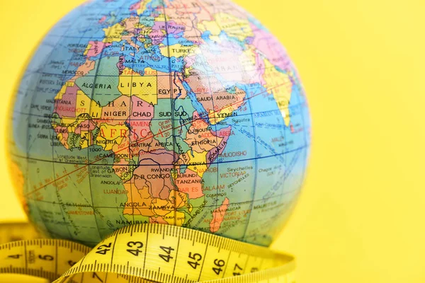 health in world concept, measuring tape and globe on yellow