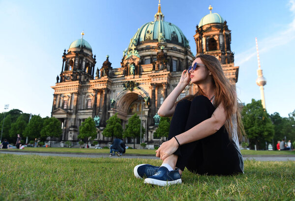 Pretty gil sitting in front of Berlin Cathedral wearing sunglusses