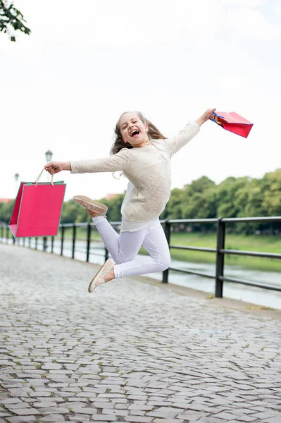 핑크 색 쇼핑백을 들고 거리를 뛰어다니는 작은 소녀 — 스톡 사진