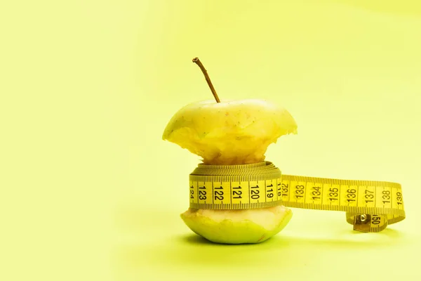 Tejp för att mäta wraps bitten äpple runt på gul bakgrund — Stockfoto