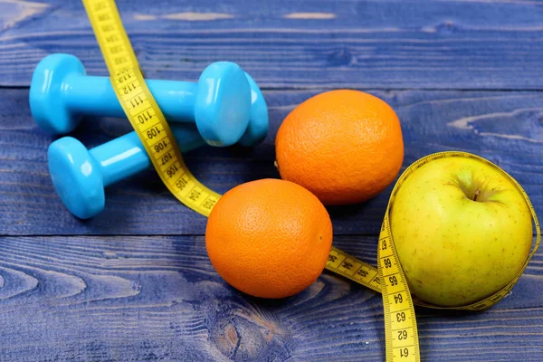 gym and health concept, dumbbells weight with measuring tape, fruit