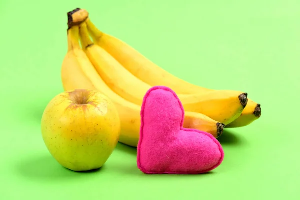 Bunch of ripe bananas next to apple and pink heart — Stock Photo, Image