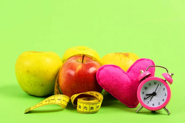 Manzanas con cinta métrica amarilla enrollada con corazón de juguete rosa —  Fotos de Stock