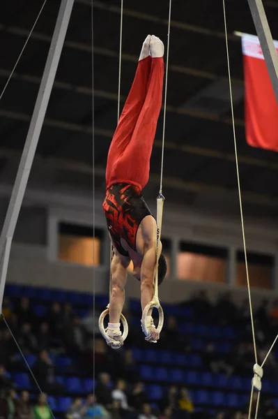 Mannelijke Turner uitvoeren op stationaire gymnastiek ringen — Stockfoto