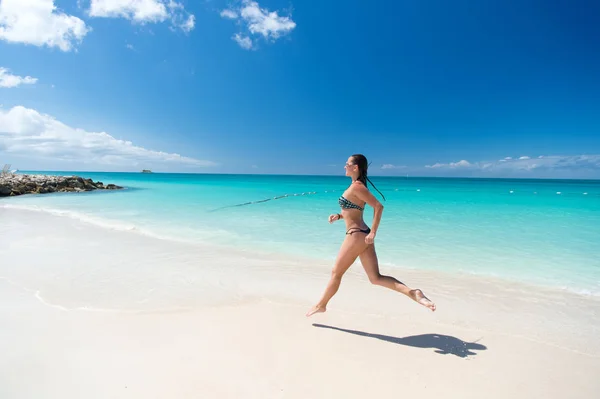 Genç bir kadın tropik sahilde koşuyor. — Stok fotoğraf