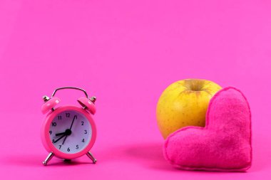 Çalar saat yanında olgun elma ve kalp