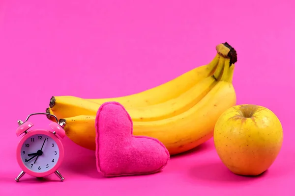 Fruit near alarm and heart, isolated on magenta pink background — Stock Photo, Image