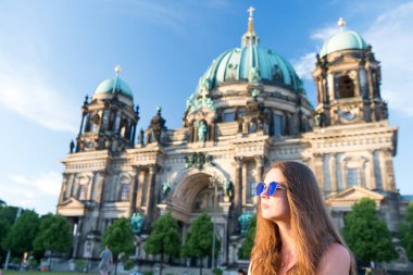 Berlin Katedrali 'nin önünde güneş kremi sürerek oturuyor.