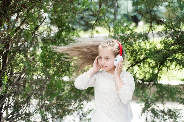 Linda niña disfrutando de la música usando auriculares —  Fotos de Stock