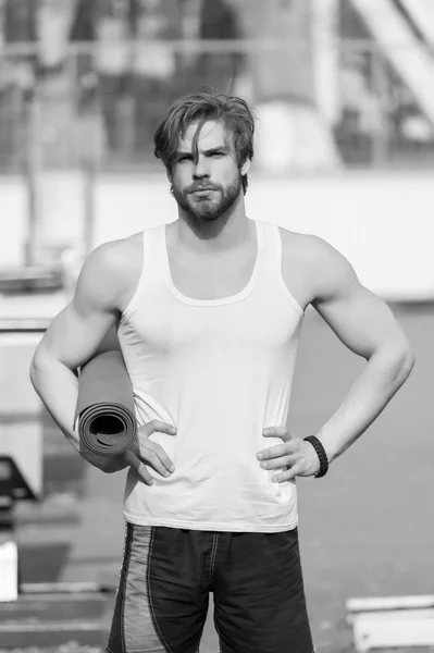 Muskularny mężczyzna trzyma mat joga lub fitness do ćwiczeń — Zdjęcie stockowe