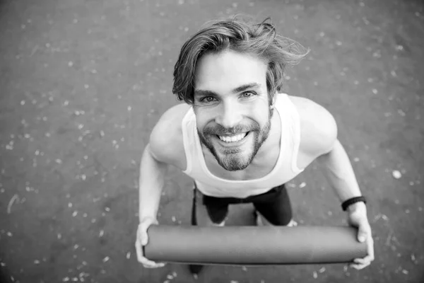 Hombre feliz con cuerpo muscular sosteniendo yoga o colchoneta de fitness — Foto de Stock