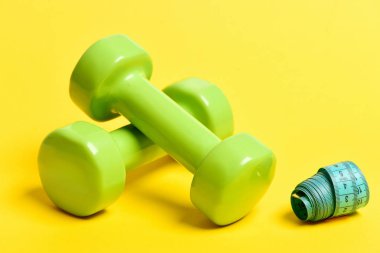 Çift parlak yeşil plastik dambıl ve haddelenmiş ölçüm bandı