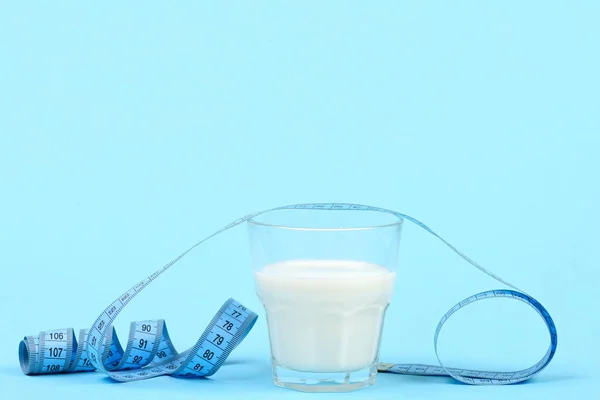 Ποτήρι γάλα και ευέλικτη χάρακα απομονώνονται σε μπλε φόντο — Φωτογραφία Αρχείου