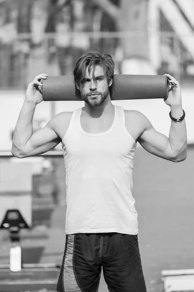 Uomo con corpo muscoloso, barba che tiene yoga o tappetino fitness — Foto Stock