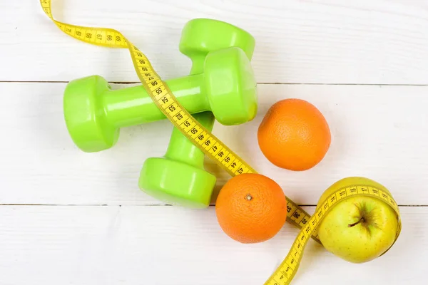 Fitness body concept, dumbbells weight with measuring tape, fruit — Stock Photo, Image