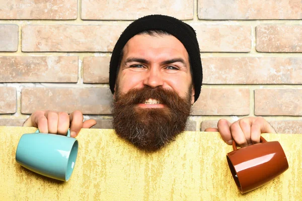 Barbudo brutal hipster caucásico con hoja de papel y tazas —  Fotos de Stock