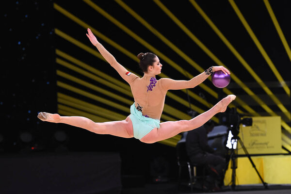 гимнастка выступает на соревнованиях по художественной гимнастике
