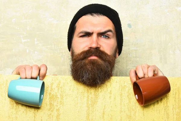 Barbudo brutal hipster caucásico con hoja de papel y tazas —  Fotos de Stock