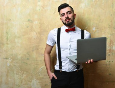 Sakallı ve kendine güveni olan menajer elinde dizüstü bilgisayar tutuyor.