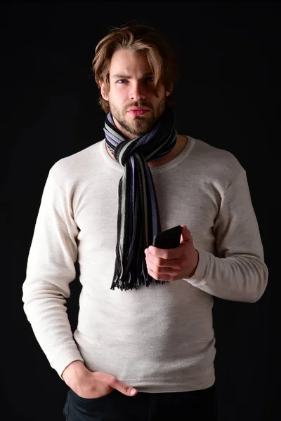 Macho with beard and stylish hairstyle, wearing scarf, holds cellphone — Stock Photo, Image