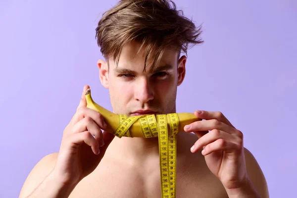 Homme tient la banane enroulée avec du ruban à mesurer jaune — Photo
