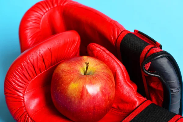 Guantes de boxeo con manzana aislada sobre fondo cian —  Fotos de Stock