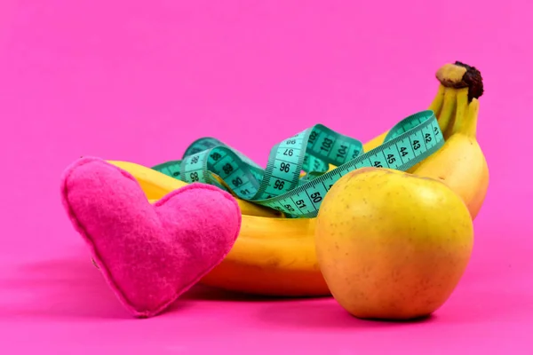 Tape for measuring on bunch of bananas, apple and heart — Stock Photo, Image