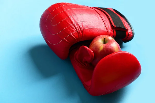 Sport equipment and fruit on bright blue background. Boxing gloves