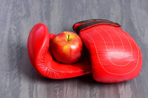 Guantes de boxeo en color rojo. Par de ropa deportiva y manzana —  Fotos de Stock