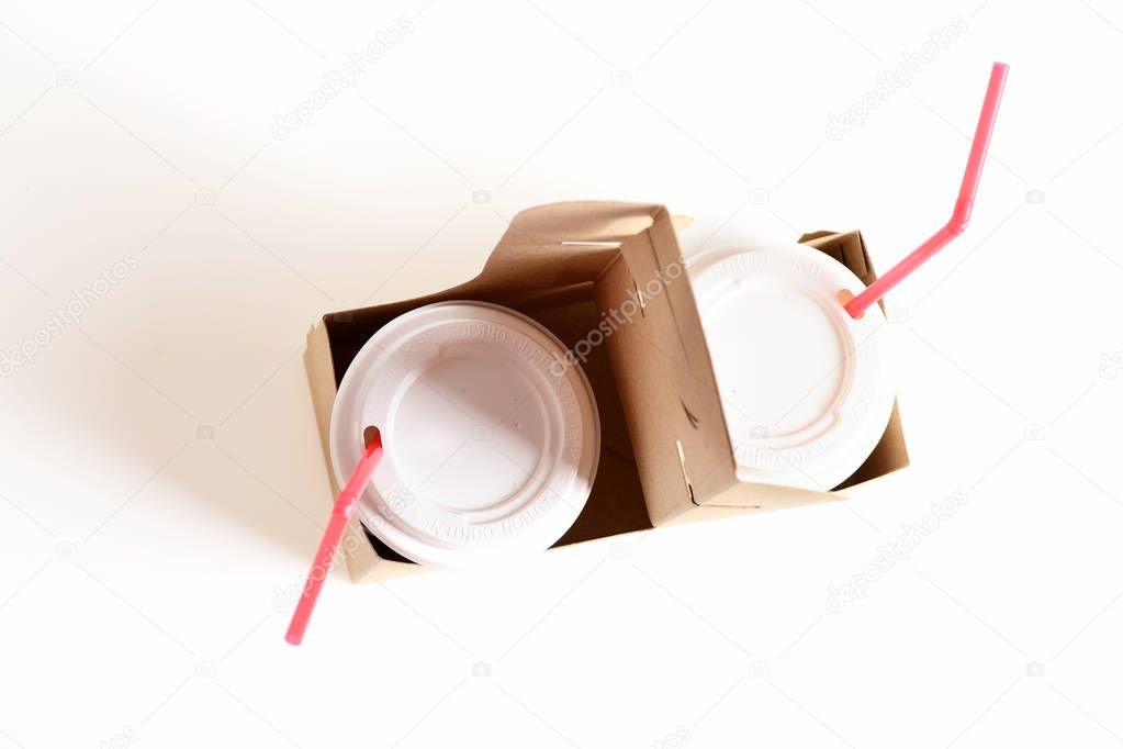Paper cups with fizzy drinks, plastic lids and red straws